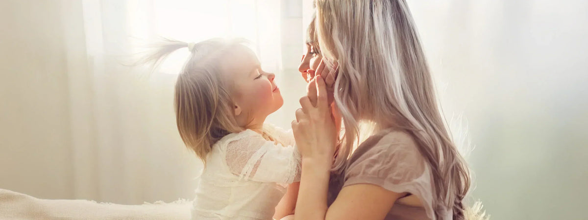 Blonde woman holding her infant daughter in a loving embrace, honoring the love of a mother this Mother's Day.