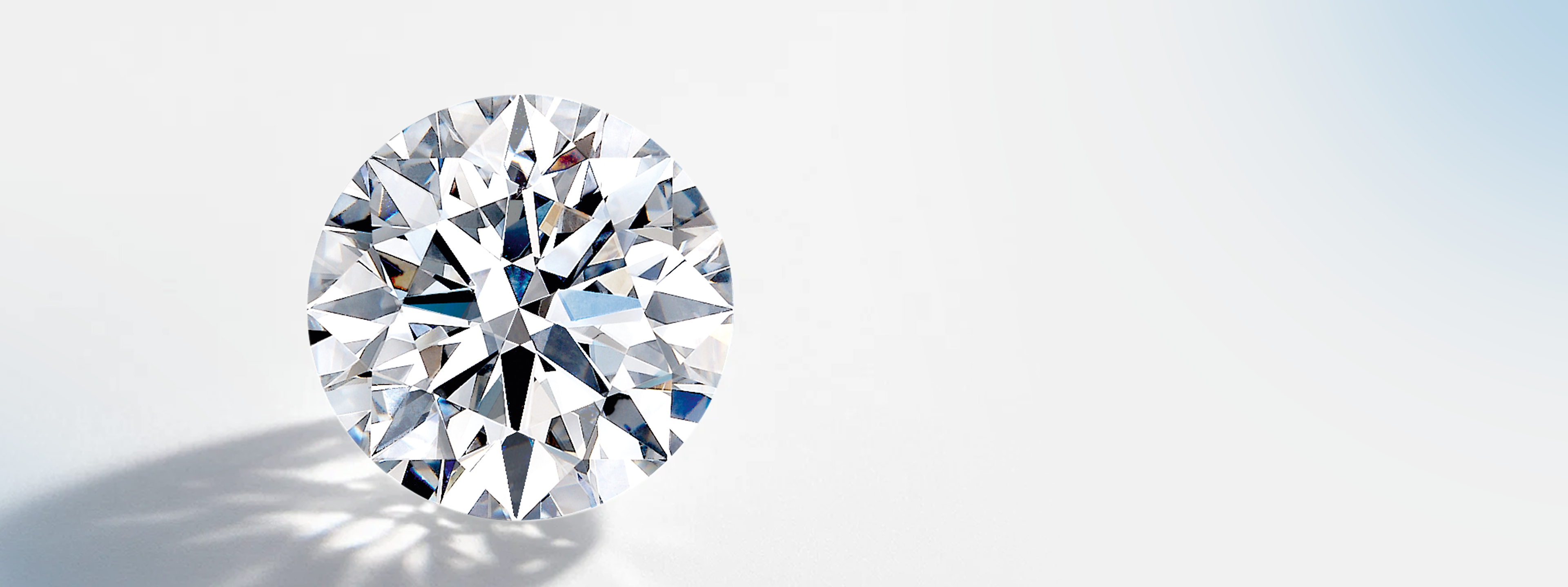 Sparkling round natural diamond with brilliant facets, reflecting light and shadow on a white surface Shimansky Eight Hearts exclusive diamond brand.
