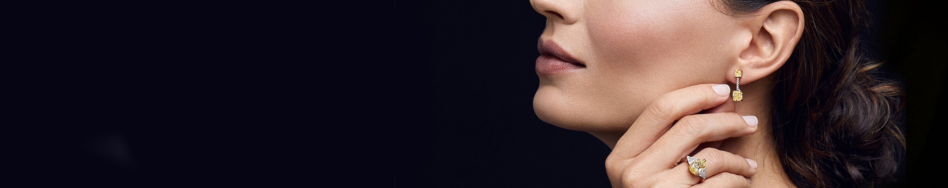 A stunning woman showcases Shimansky's fancy yellow diamond earrings, epitomizing elegance and opulence.