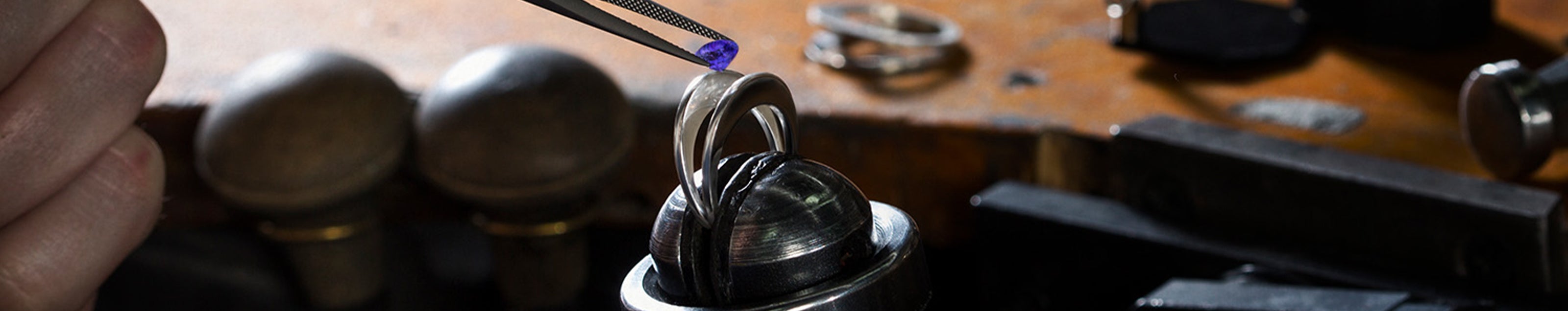 A skilled artisan delicately cuts a ring featuring a stunning Tanzanite stone at Shimansky with elegant scissors.