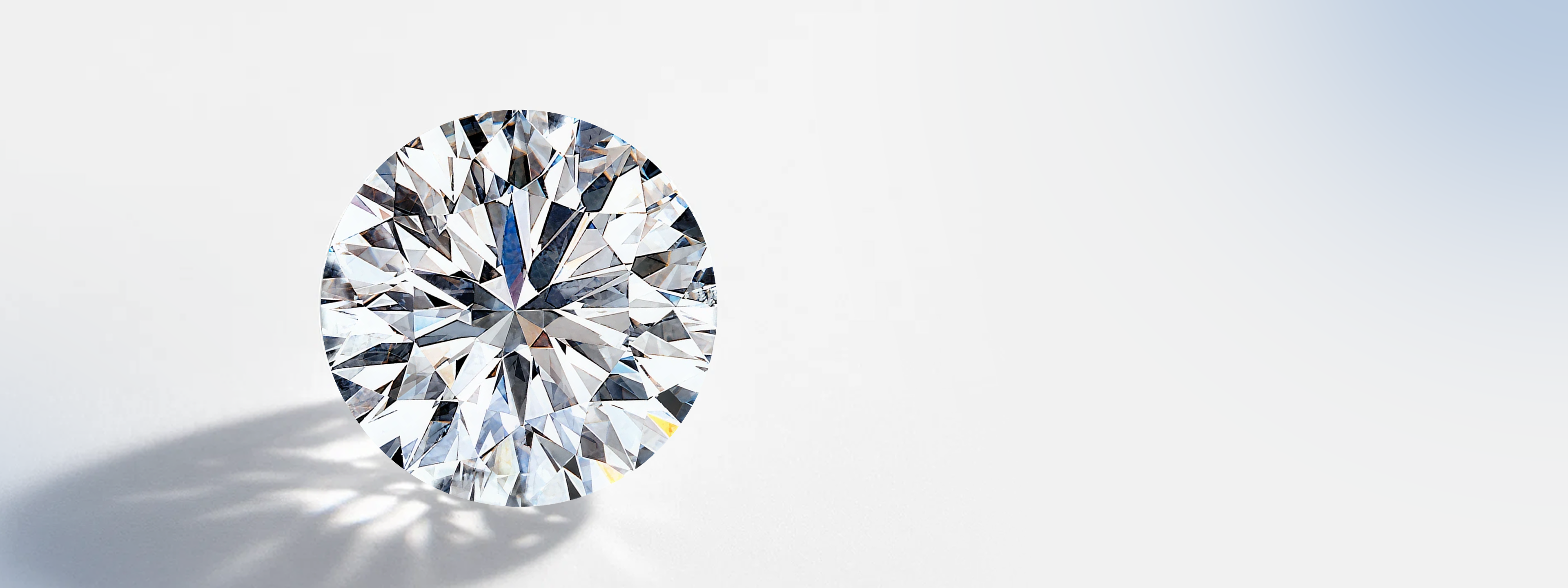 Sparkling Brilliant 10 natural diamond with brilliant facets, reflecting light and shadow on a white surface Shimansky Brilliant 10 exclusive diamond brand