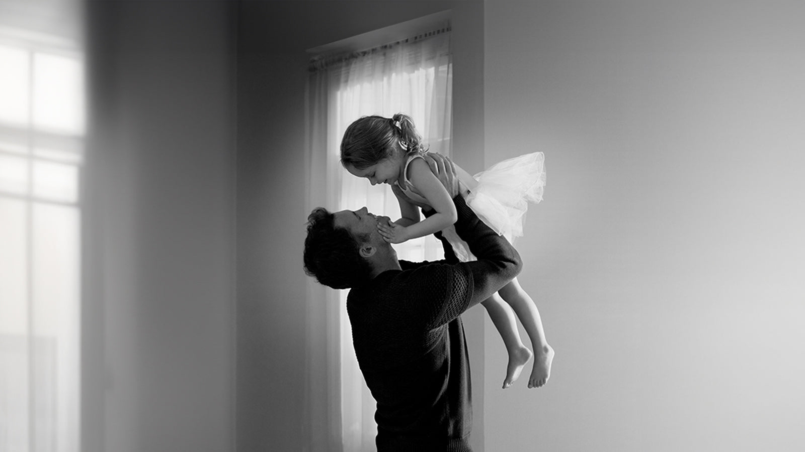 A joyful father lifts a little girl high above, capturing a moment of pure happiness and connection between them.