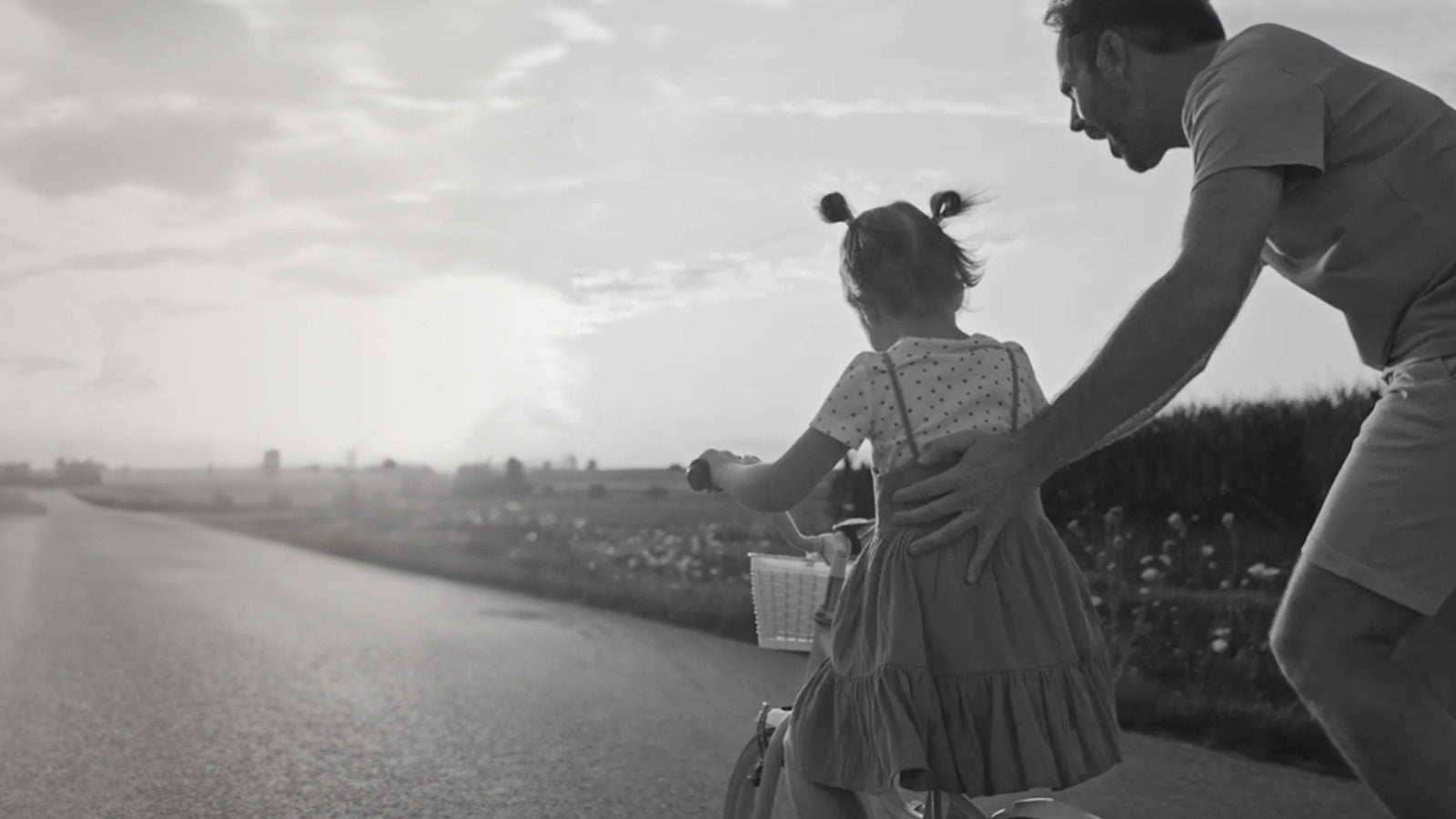 A father and daughter joyfully cycling together on a picturesque country road, surrounded by lush greenery and tranquility.