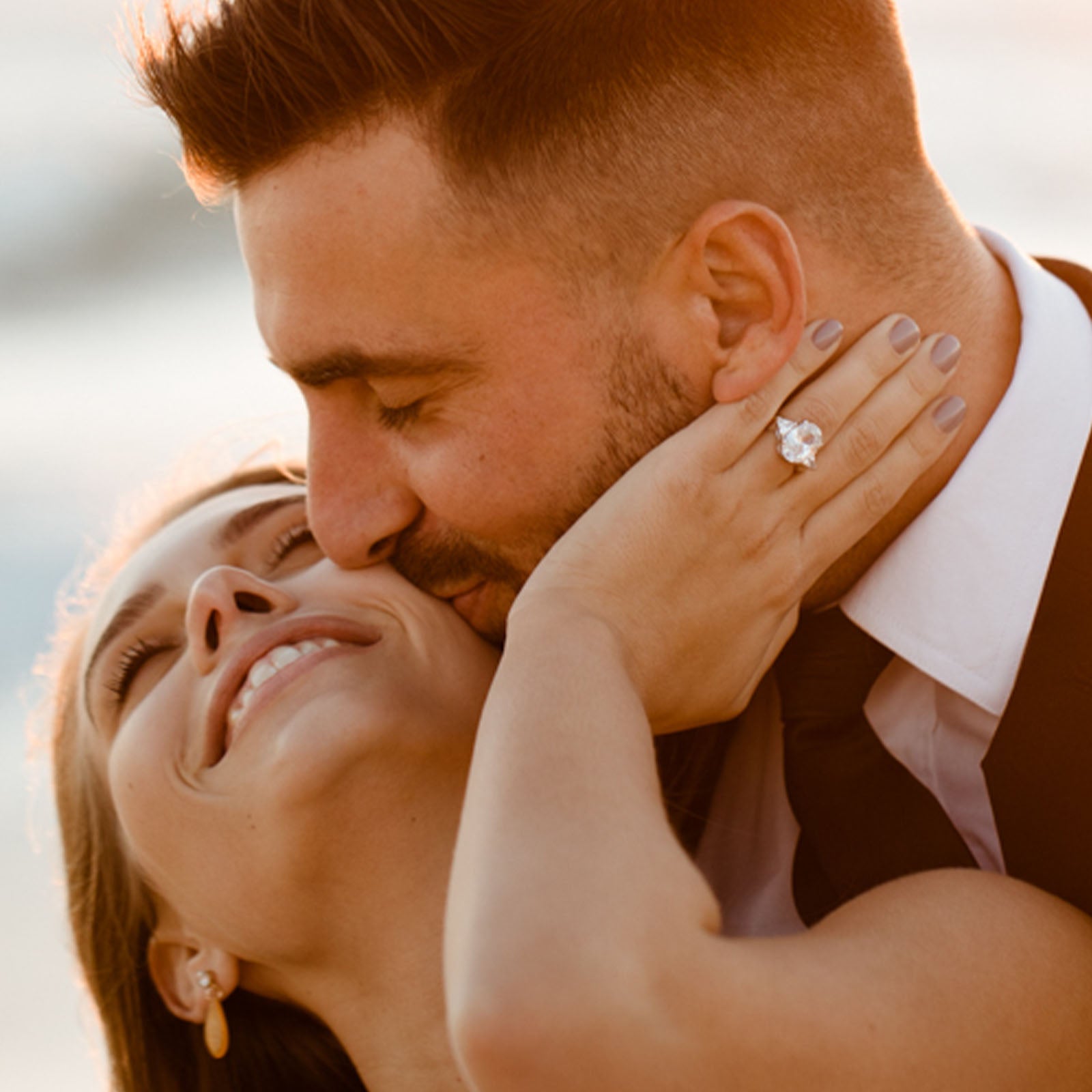 A couple shares a tender embrace on the beach, surrounded by soft sand and the calming sound of ocean waves.