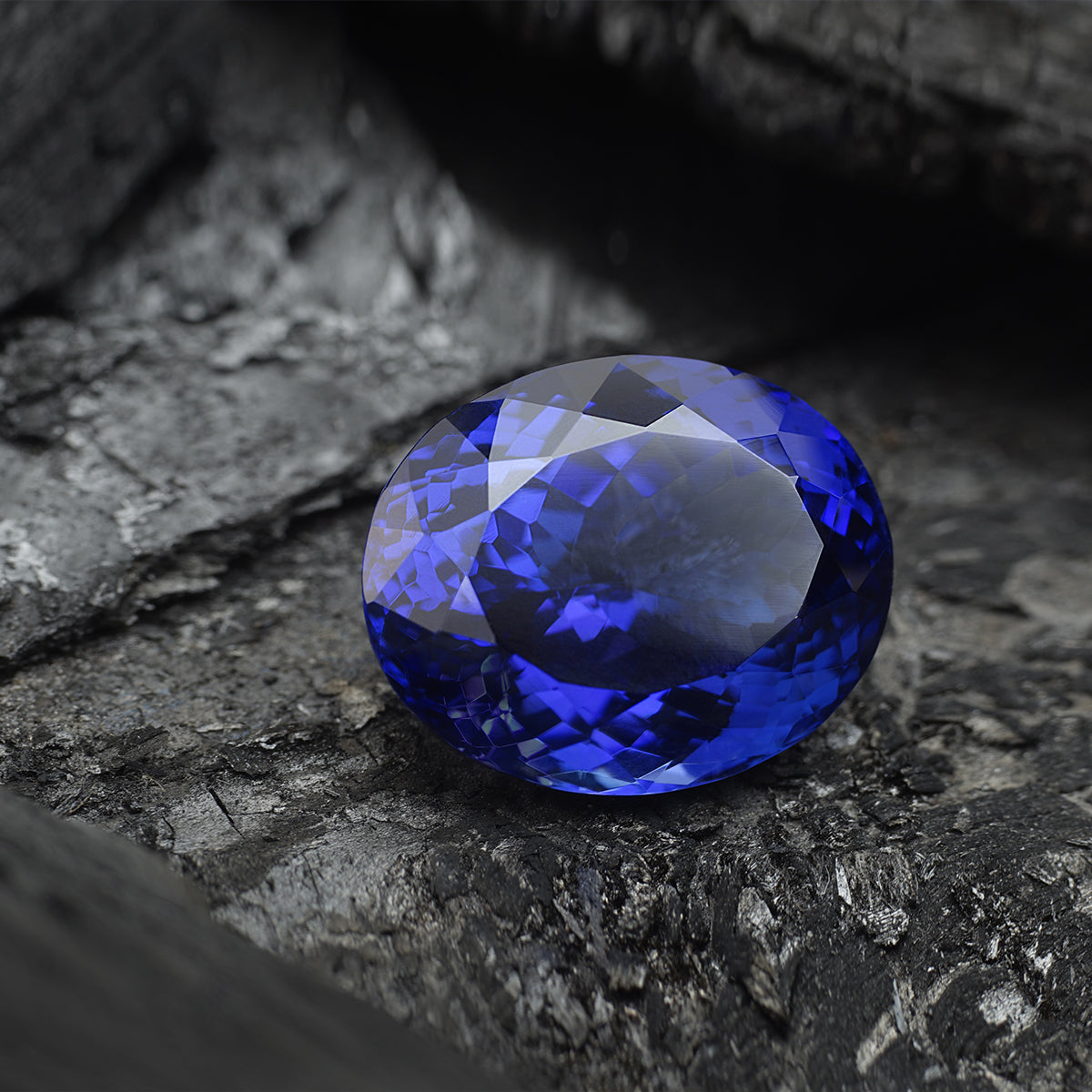 Shimansky Cut Tanzanite sitting on black charcoal.