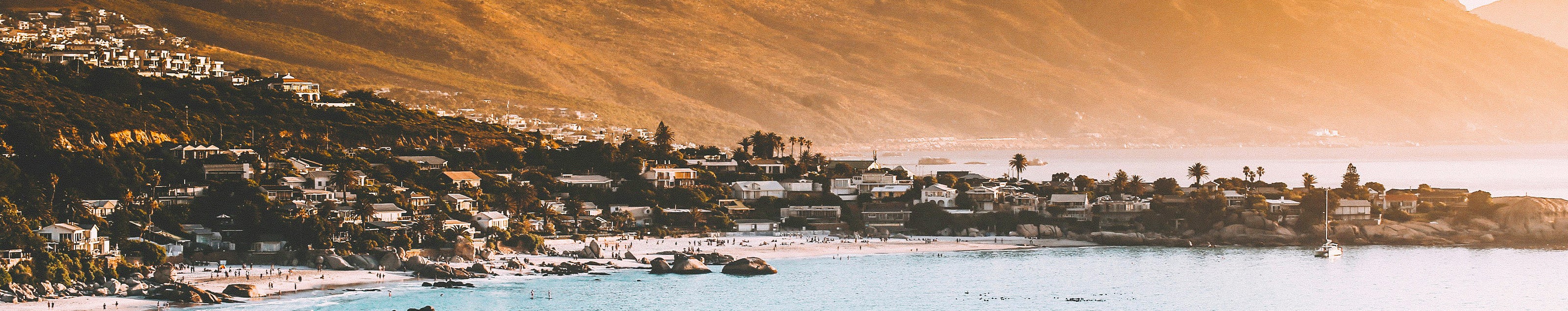 A stunning coastal view of Cape Town, South Africa, showcasing vibrant buildings against a backdrop of azure waters.