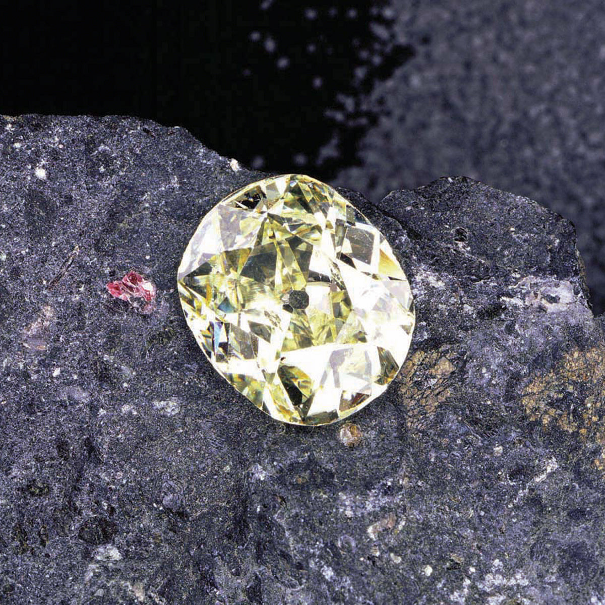 A radiant yellow diamond rests gracefully on a textured rock, highlighting its exquisite color and luxurious allure.