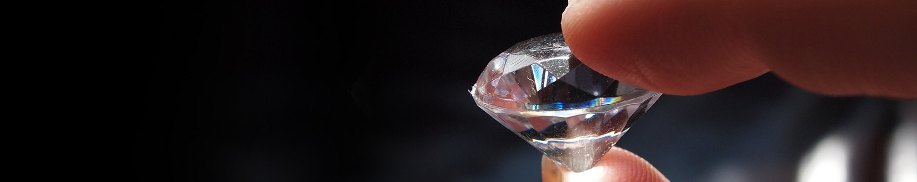 A person delicately holds a radiant diamond, showcasing its exquisite beauty and timeless elegance.