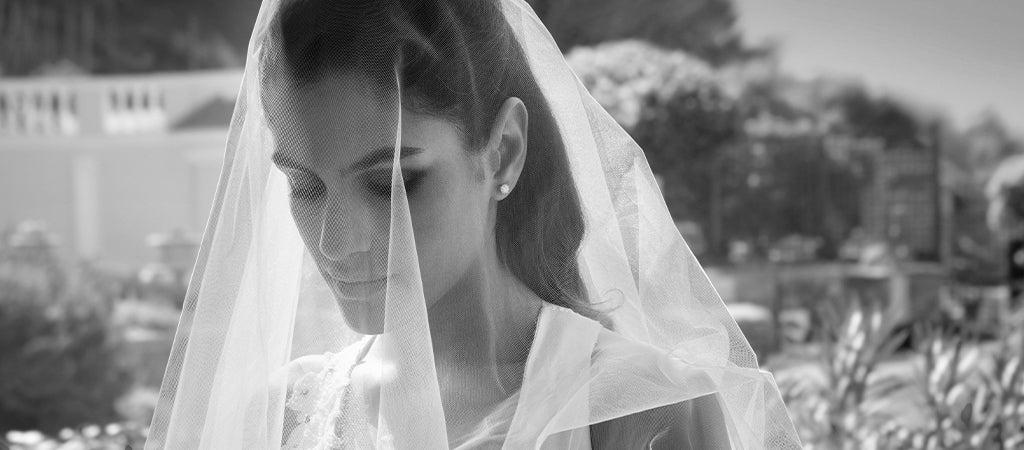 A beautiful woman in a stunning wedding gown looks down thoughtfully, capturing a moment of elegance and reflection.