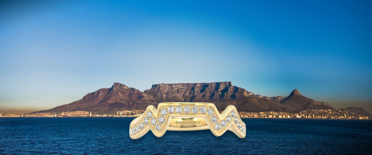 A stunning Cape Town diamond ring glistens against a majestic Table Mountain backdrop in Cape Town. By Shimansky