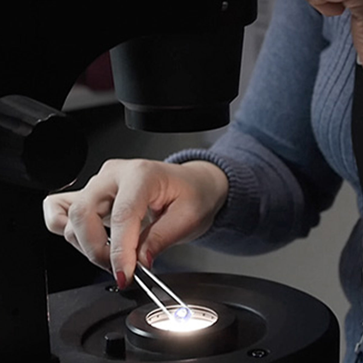 Woman inspecting a Tanzanite gem under a microscope