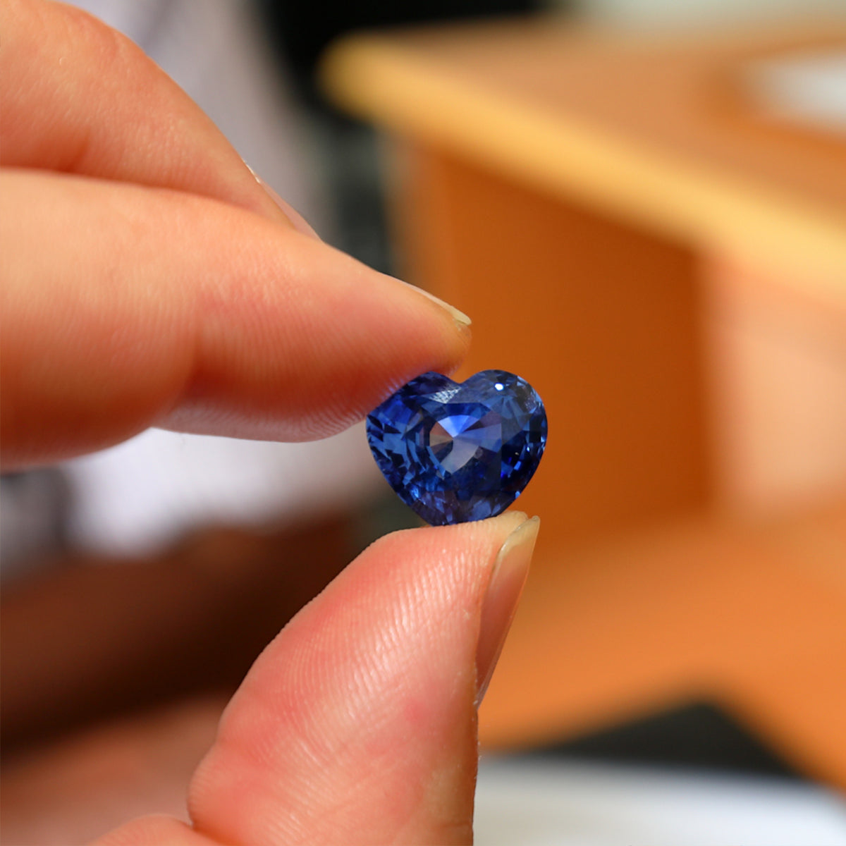 A hand showcases a heart-shaped tanzanite stone, symbolizing exquisite elegance and beauty.