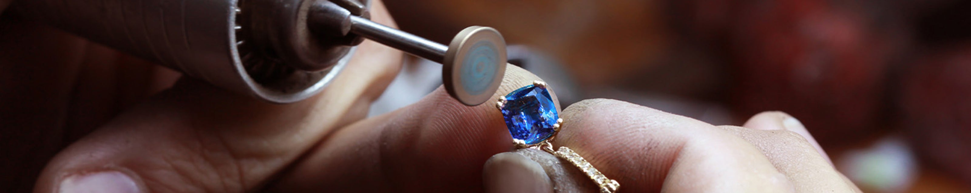 An artisan delicately works on a stunning gemstone, nestled in a gold ring, featuring tanzanite from Shimansky.