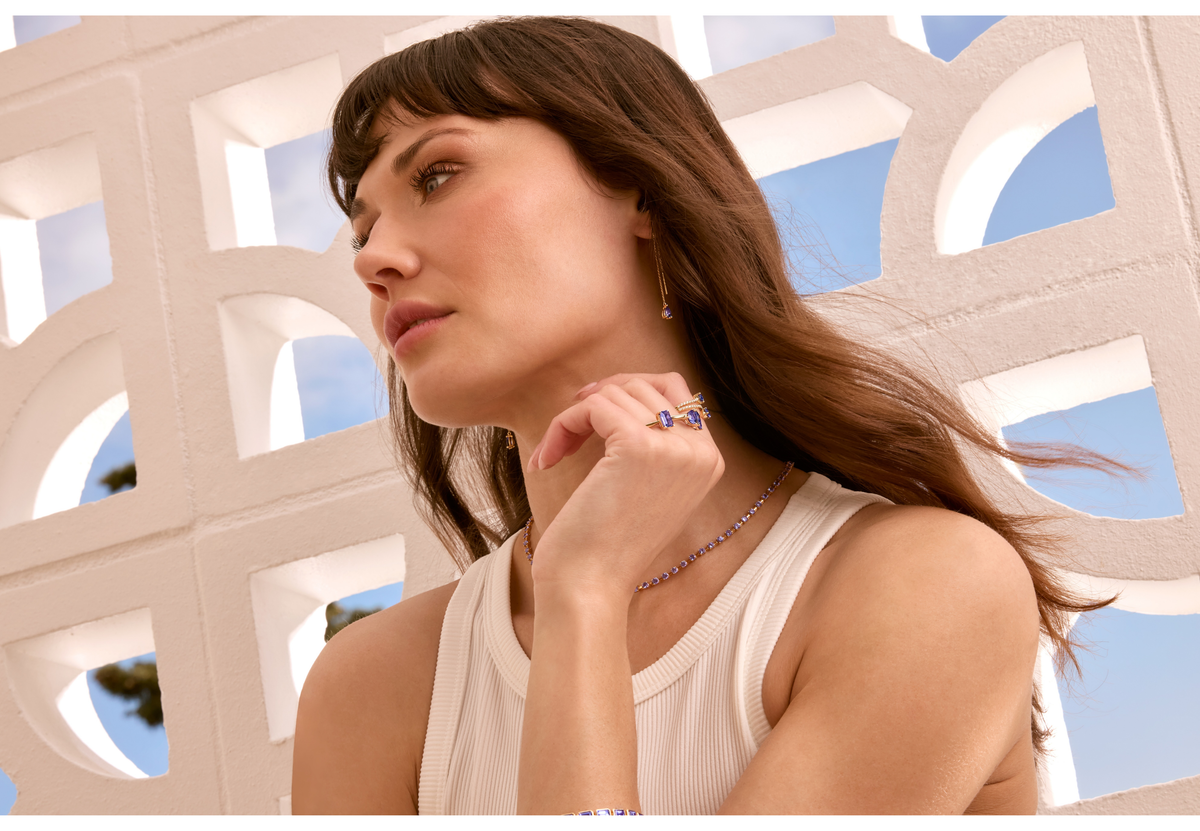 Shimansky fine Tanzanite tennis necklace and yellow gold Tanzanite rings, worn outdoors with a cream top.