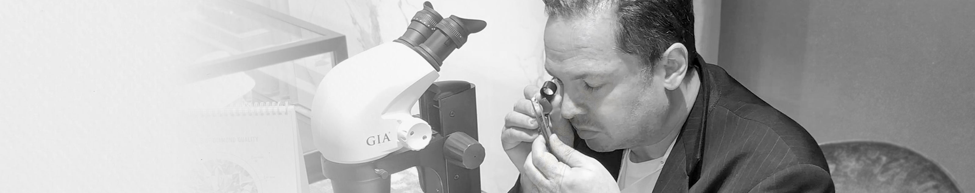 Yair Shimansky, elegantly attired, inspects a diamond with a microscope, embodying luxury and meticulous craftsmanship.