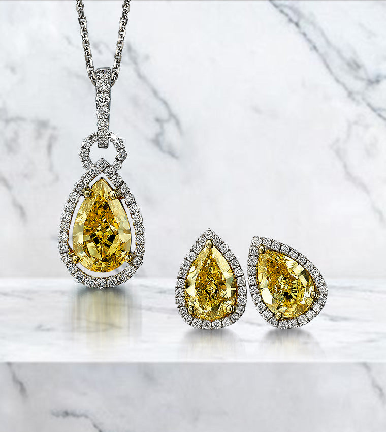 A stunning yellow diamond pendant and earrings elegantly displayed on a luxurious marble surface, showcasing their brilliance.