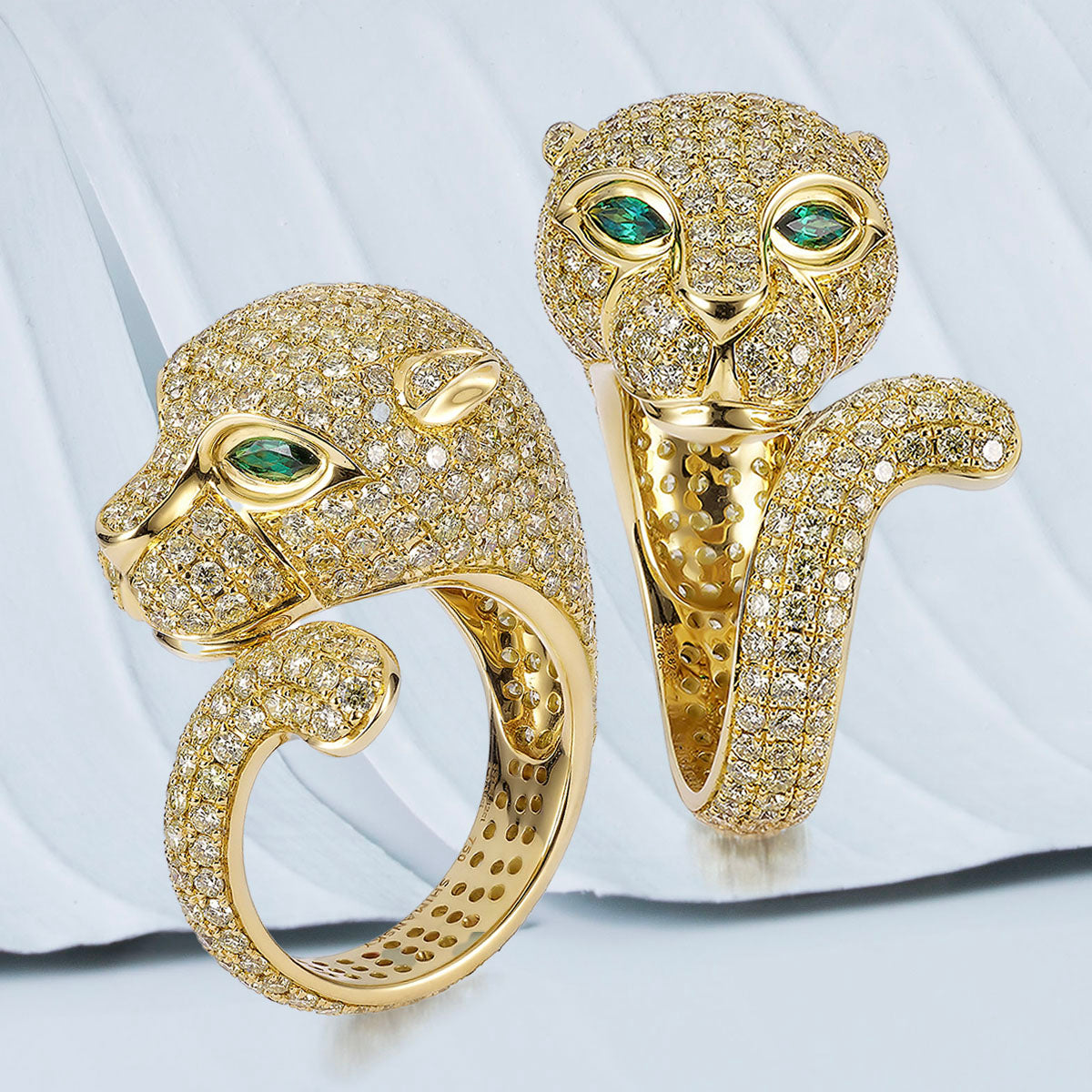 Two exquisite yellow gold rings adorned with emeralds and diamonds, showcasing the elegance of Shimansky's Africa Panther design.